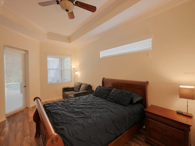 bedroom with crown molding, dark hardwood / wood-style floors, a tray ceiling, and ceiling fan