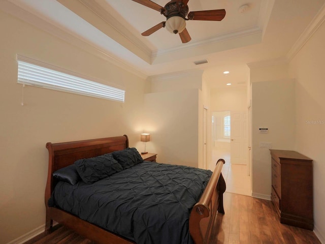 bedroom featuring crown molding, dark hardwood / wood-style floors, a tray ceiling, and ceiling fan