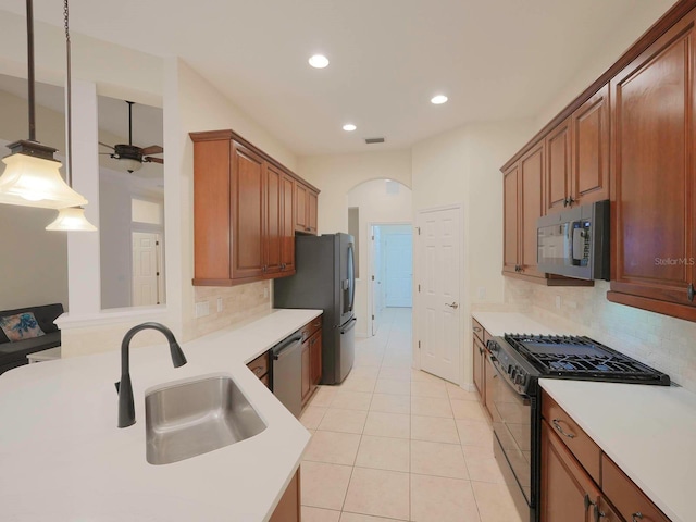 kitchen featuring pendant lighting, stainless steel appliances, sink, backsplash, and light tile patterned flooring