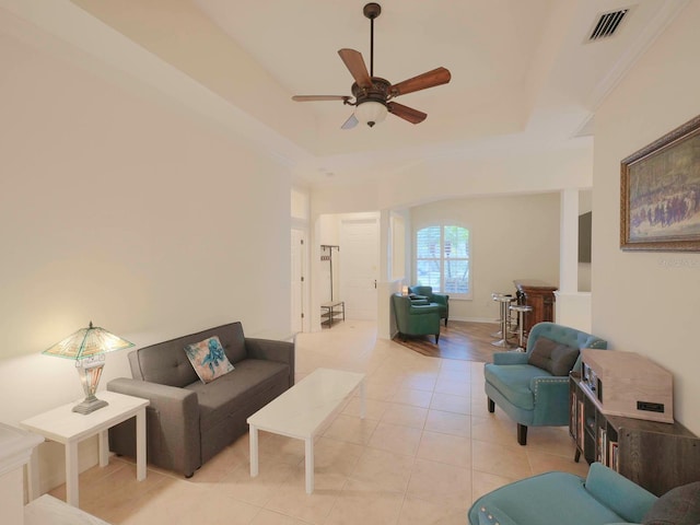 living room featuring ceiling fan, a raised ceiling, and light tile patterned floors