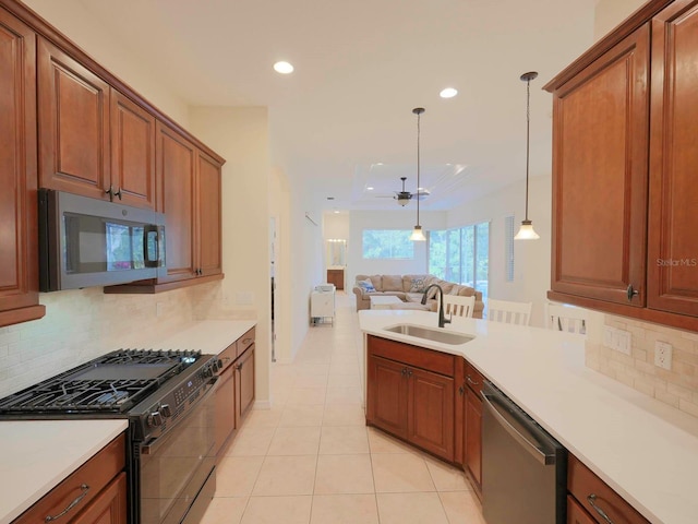 kitchen with decorative light fixtures, stainless steel appliances, sink, backsplash, and light tile patterned floors