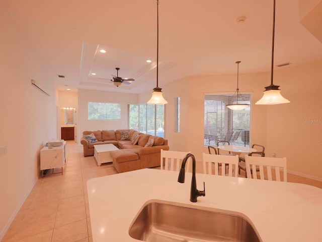 kitchen with sink, plenty of natural light, pendant lighting, and a raised ceiling