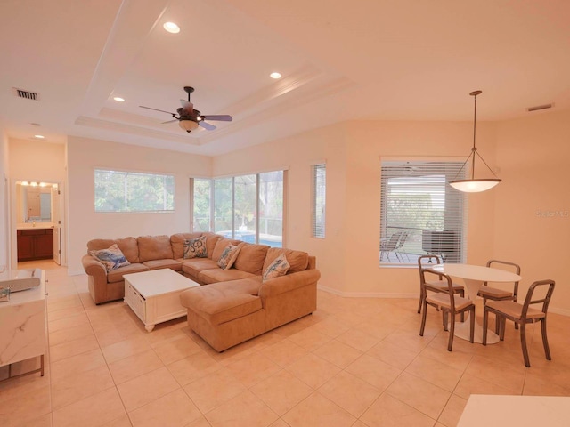 living room featuring ceiling fan, a raised ceiling, and light tile patterned flooring