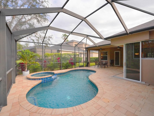 view of pool with an in ground hot tub, a patio area, glass enclosure, and ceiling fan