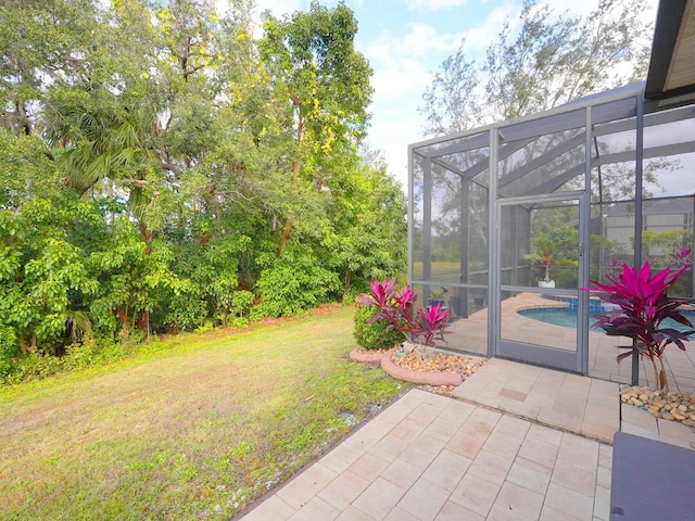 view of yard with glass enclosure and a patio area