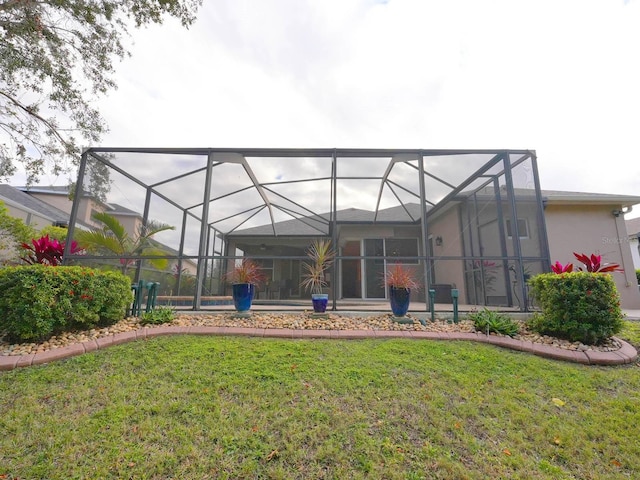 back of property with glass enclosure and a lawn