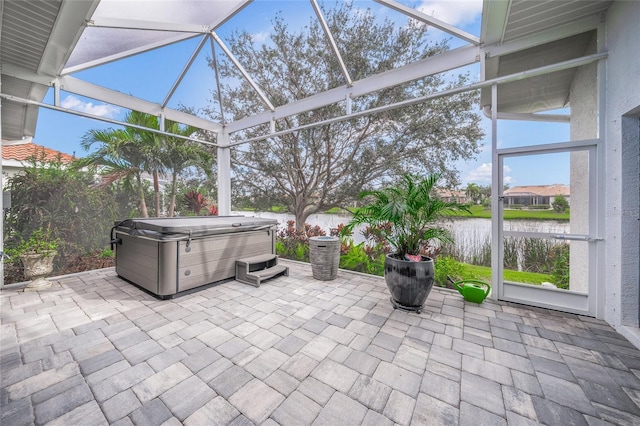 view of patio / terrace with a lanai, a water view, and a hot tub