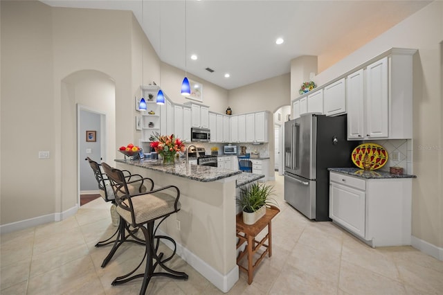 kitchen featuring white cabinets, a breakfast bar, dark stone countertops, and stainless steel appliances