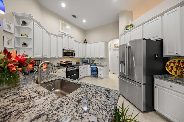 kitchen featuring white cabinets, dark stone counters, sink, and stainless steel appliances