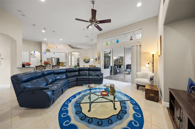 living room featuring ceiling fan, light tile patterned floors, and a towering ceiling