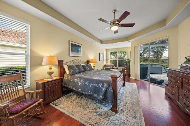 bedroom with ceiling fan, access to exterior, dark hardwood / wood-style flooring, and multiple windows