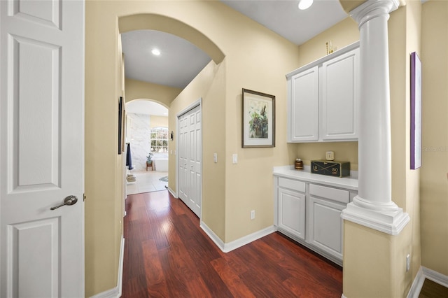 hallway with dark wood-type flooring and decorative columns