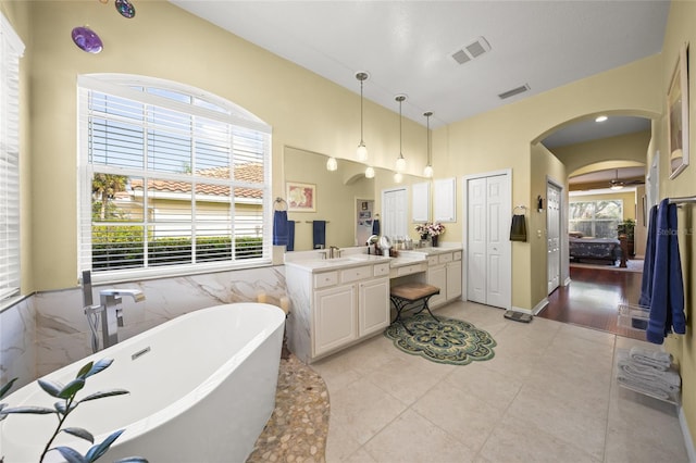 bathroom featuring tile patterned flooring, tile walls, a bathtub, and vanity