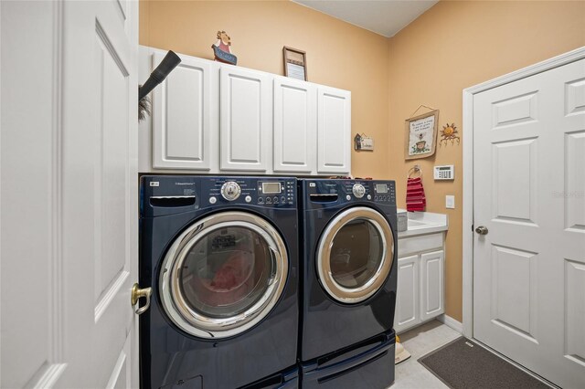 laundry room featuring washer and dryer and cabinets