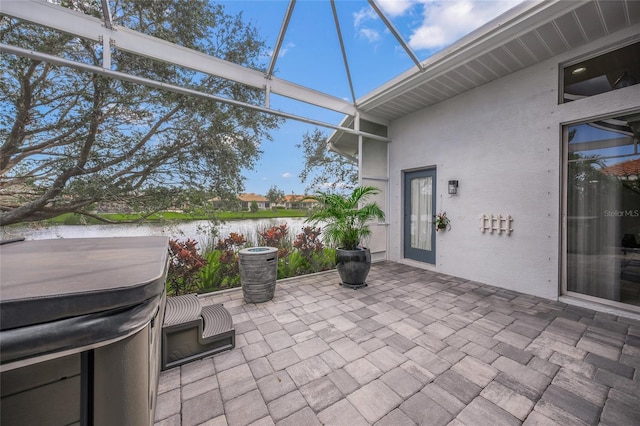 view of patio / terrace featuring a water view and a hot tub