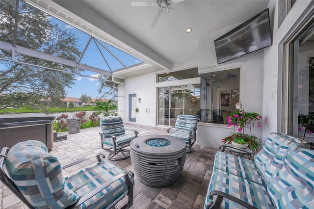 view of patio with a lanai, ceiling fan, and a fire pit