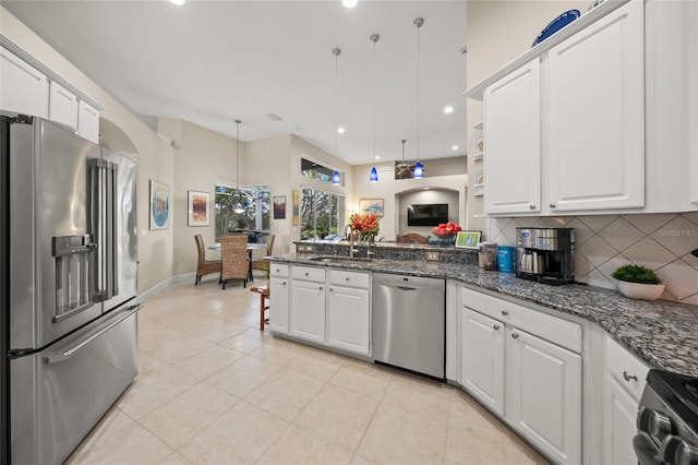 kitchen with appliances with stainless steel finishes, tasteful backsplash, hanging light fixtures, white cabinets, and sink