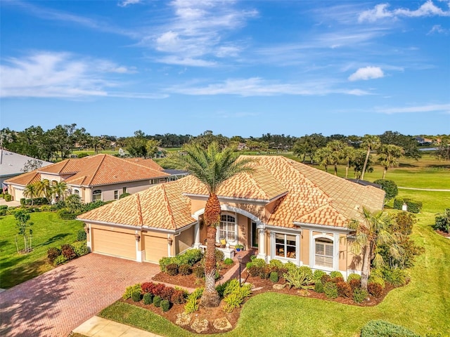 mediterranean / spanish house with a garage, a tile roof, decorative driveway, and stucco siding