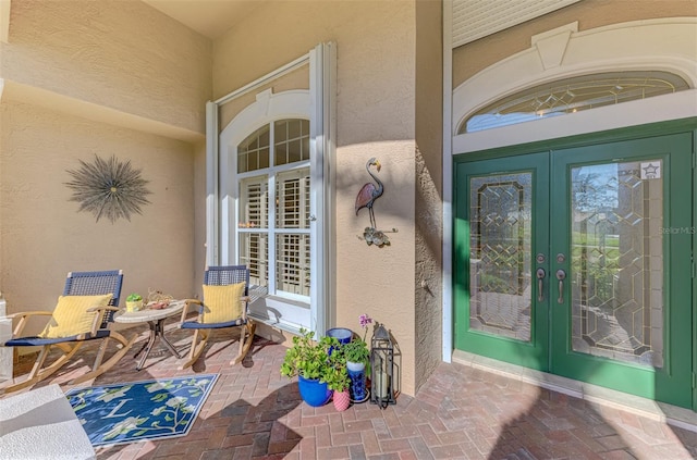 view of exterior entry featuring french doors and stucco siding