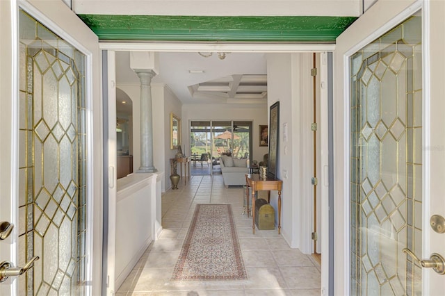 foyer featuring beamed ceiling, coffered ceiling, light tile patterned flooring, and ornate columns