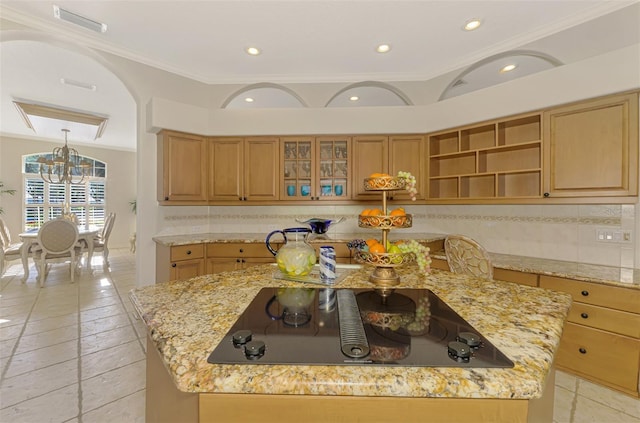 kitchen featuring black electric stovetop, a kitchen island, backsplash, and visible vents