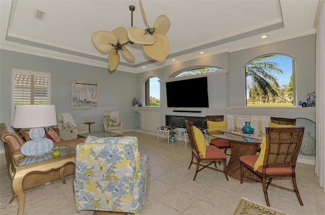 living area with a tray ceiling, recessed lighting, visible vents, a ceiling fan, and ornamental molding