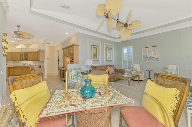 dining space with arched walkways, a tray ceiling, crown molding, light tile patterned floors, and ceiling fan