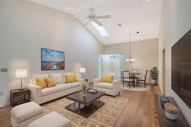 living room with high vaulted ceiling, ceiling fan with notable chandelier, and light hardwood / wood-style flooring