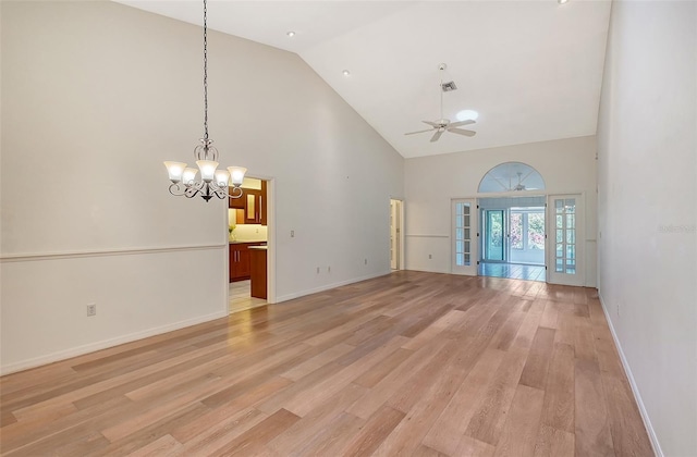 unfurnished living room with high vaulted ceiling, ceiling fan with notable chandelier, and light hardwood / wood-style floors