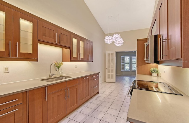 kitchen with light tile patterned floors, stovetop, vaulted ceiling, pendant lighting, and sink