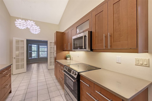 kitchen with light tile patterned flooring, pendant lighting, appliances with stainless steel finishes, french doors, and vaulted ceiling