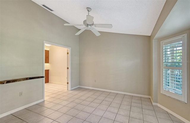 unfurnished room featuring lofted ceiling, ceiling fan, light tile patterned flooring, and a textured ceiling