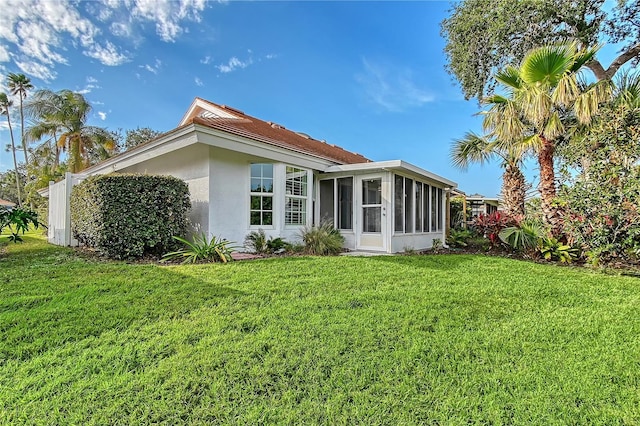 back of property featuring a sunroom and a lawn