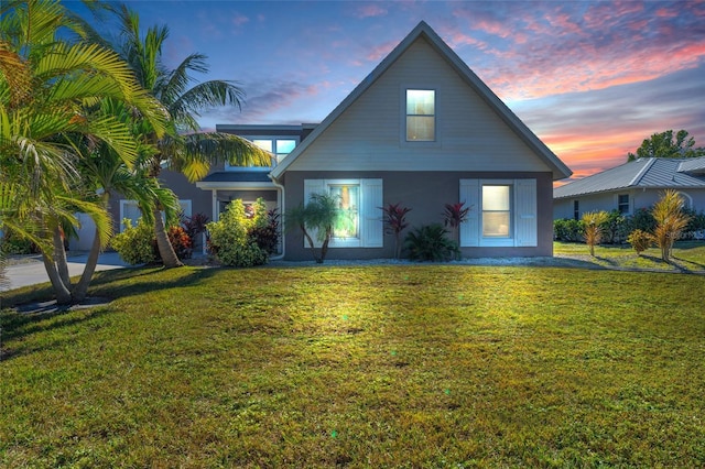 back house at dusk featuring a lawn