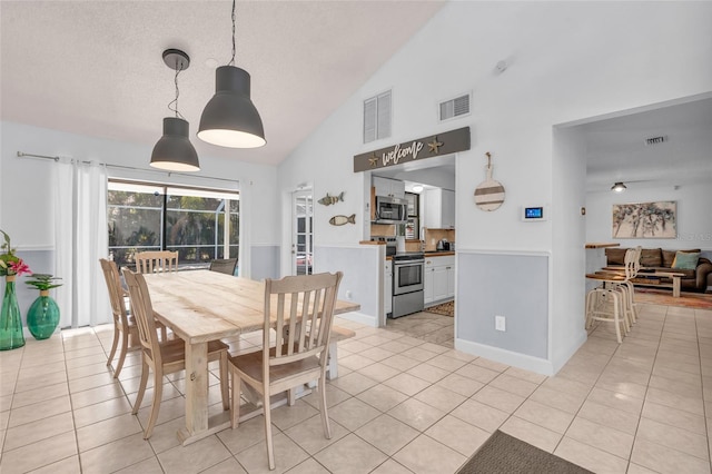 tiled dining area with a textured ceiling and vaulted ceiling