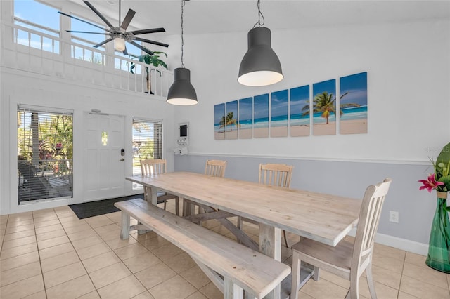 tiled dining room featuring ceiling fan, a healthy amount of sunlight, and a high ceiling