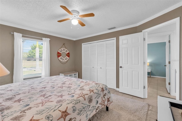 tiled bedroom featuring ceiling fan, a closet, ornamental molding, and a textured ceiling