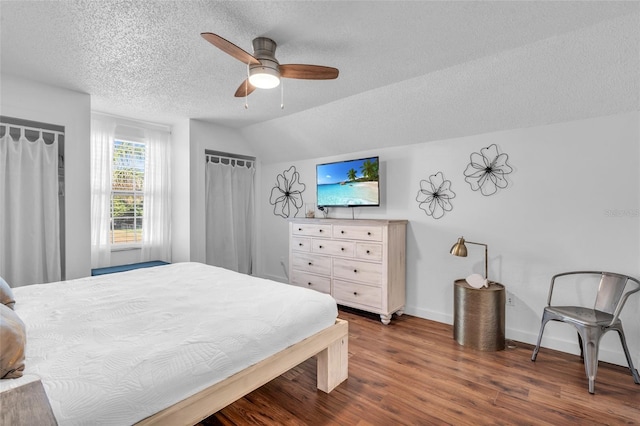 bedroom with ceiling fan, vaulted ceiling, dark hardwood / wood-style flooring, and a textured ceiling