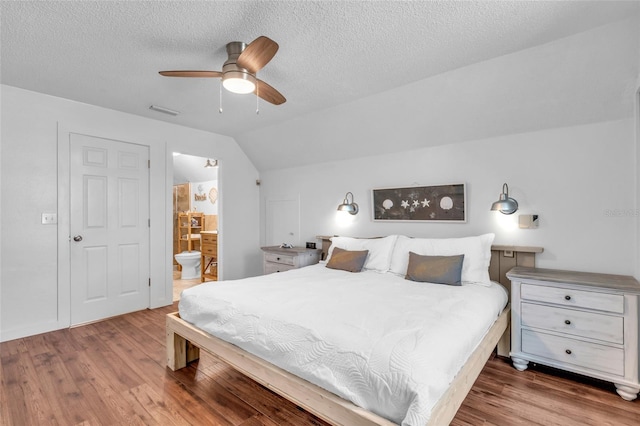 bedroom featuring ceiling fan, ensuite bathroom, lofted ceiling, and hardwood / wood-style floors