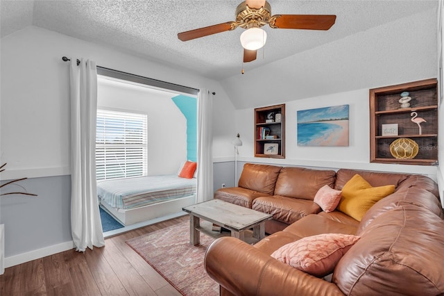 living room with ceiling fan, wood-type flooring, built in features, and vaulted ceiling