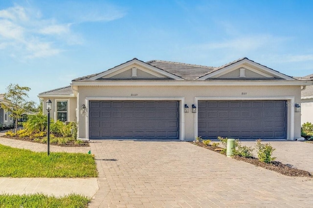 ranch-style house featuring decorative driveway, an attached garage, and stucco siding