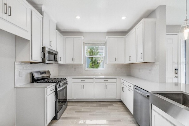 kitchen featuring wood tiled floor, appliances with stainless steel finishes, white cabinets, and backsplash