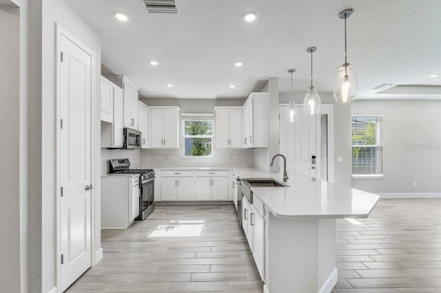 kitchen featuring plenty of natural light, stainless steel appliances, a peninsula, and visible vents