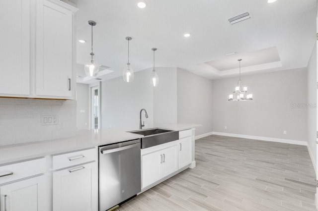 kitchen with a sink, visible vents, stainless steel dishwasher, light wood finished floors, and a raised ceiling