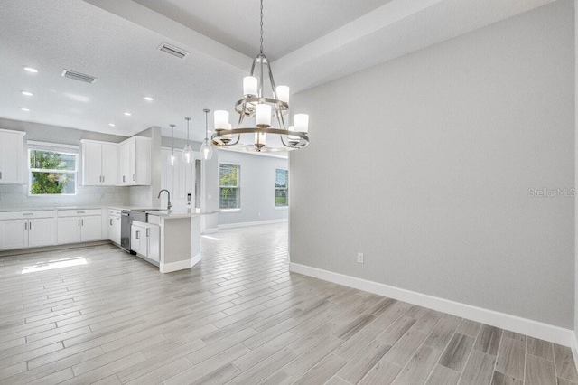 kitchen featuring light countertops, visible vents, stainless steel dishwasher, open floor plan, and a peninsula