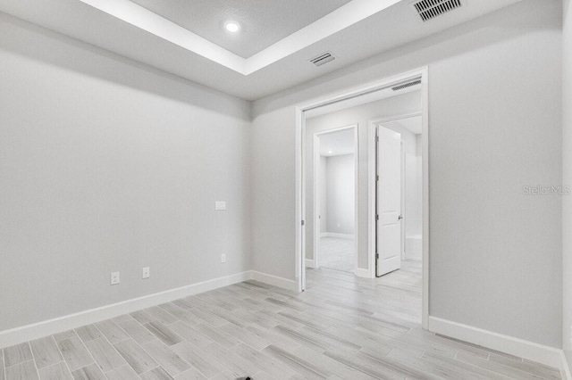 empty room with recessed lighting, light wood-type flooring, visible vents, and baseboards