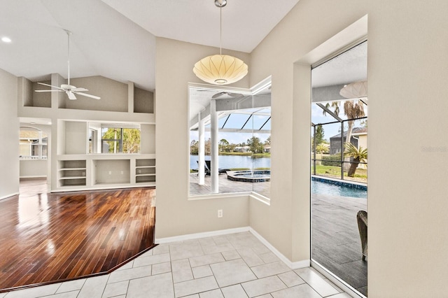 interior space with ceiling fan, a water view, a wealth of natural light, and light tile patterned floors