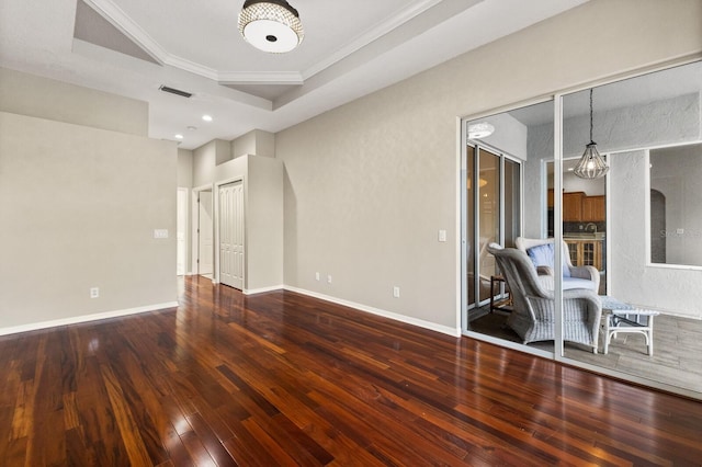 spare room featuring crown molding, hardwood / wood-style floors, a chandelier, and a tray ceiling