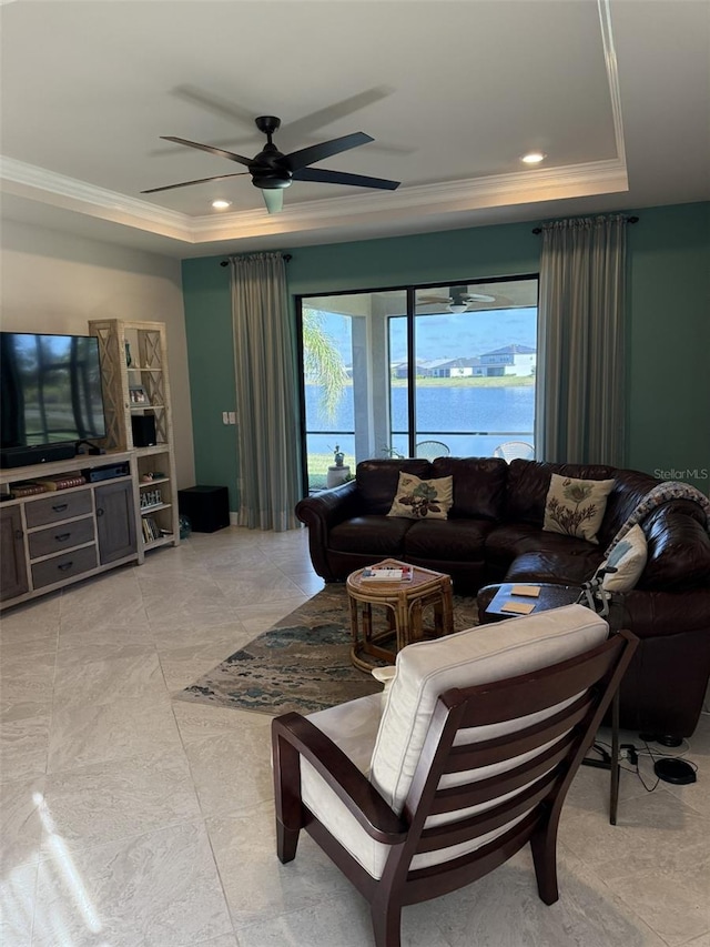 living room featuring a water view, ceiling fan, ornamental molding, and a tray ceiling