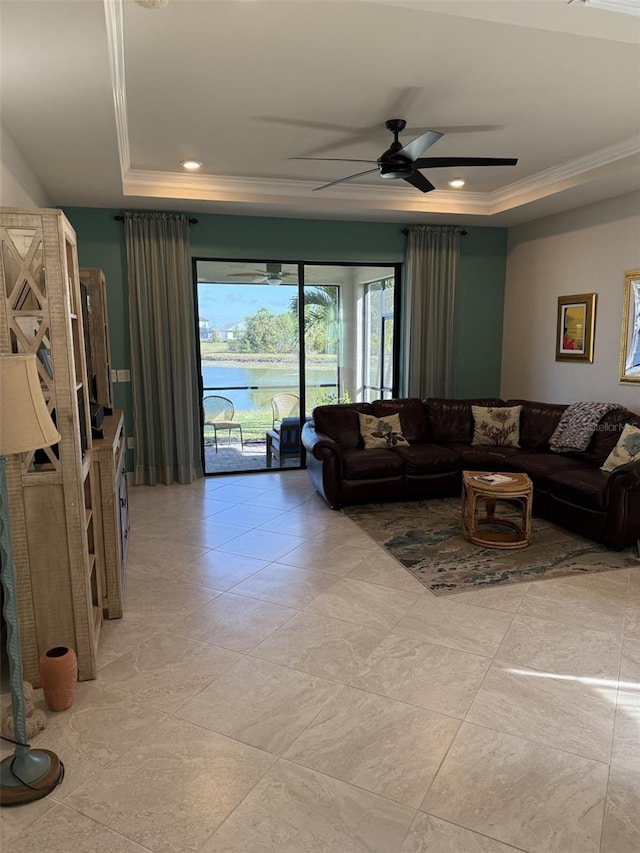 living room featuring a water view, ceiling fan, a tray ceiling, and crown molding